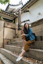 Young happy girl on backpacking vacation sitting onÃÂ the stairs in Japan. elegant traveler waiting for the tour guide in osaka